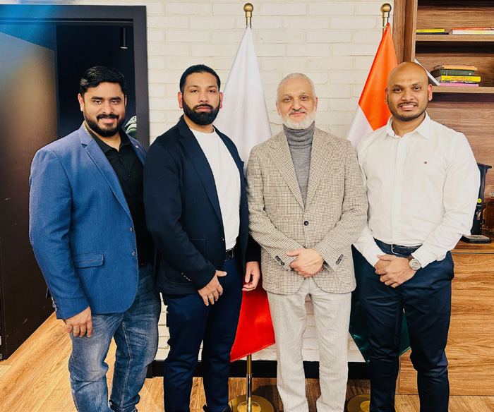 Muneer Shaikh with guests in front of Polish and Indian flags